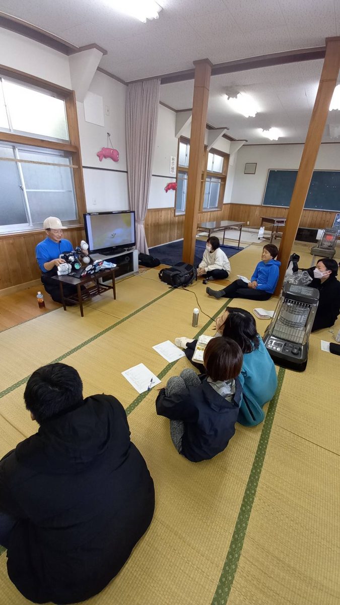 和室で、参加者が画面を囲んでセミナーを受けている様子