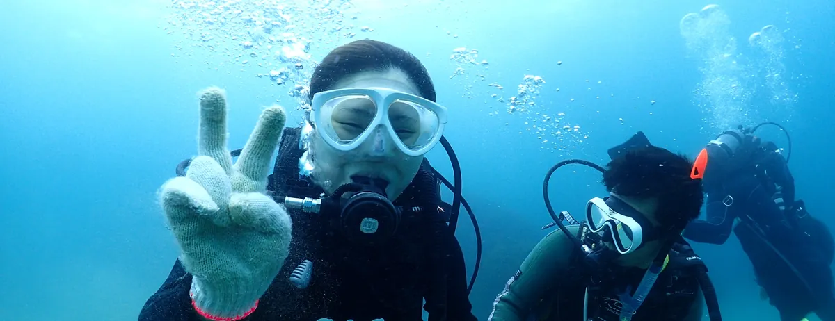佐渡の海で笑顔でピースをするダイバー